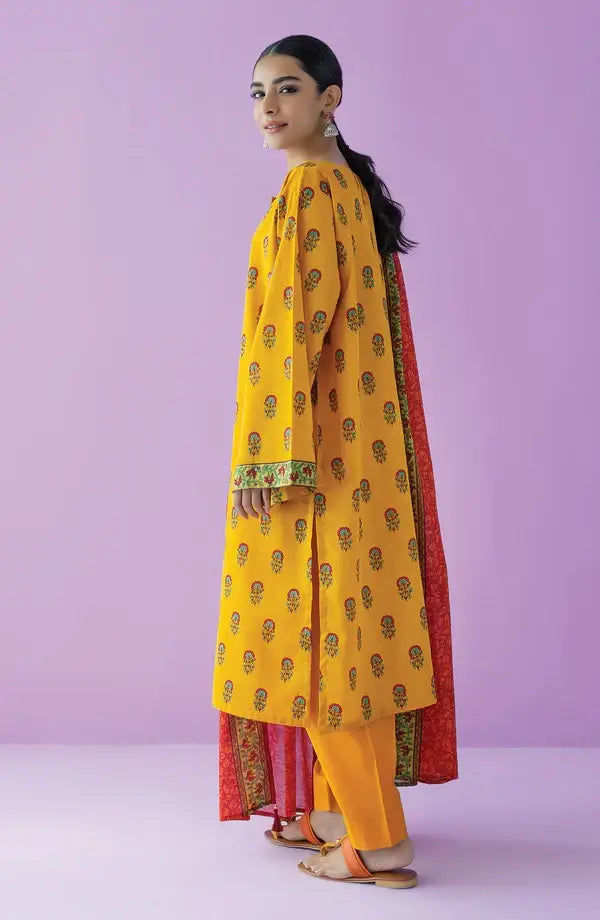 A woman modeling a yellow kurta with small printed motifs, paired with orange pants and a red dupatta, set against a solid lavender studio background.