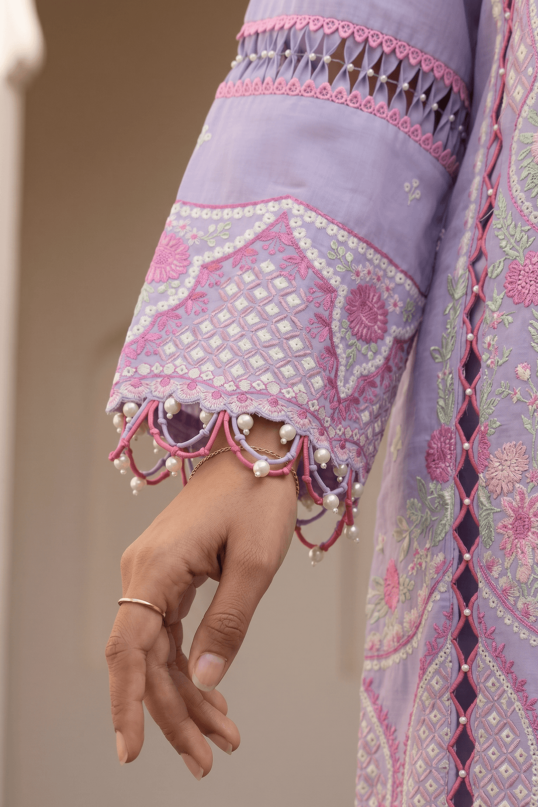 Close-up of a hand wearing a ring with a purple embroidered garment in the background