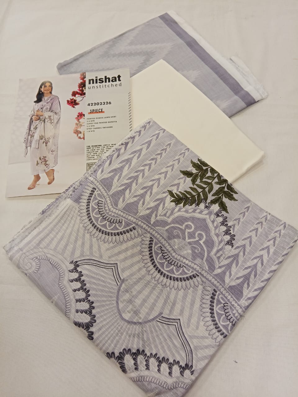 Flat lay showcasing the complete Nishat 3pc Unstitched Doriya Lawn Ash White unstitched set