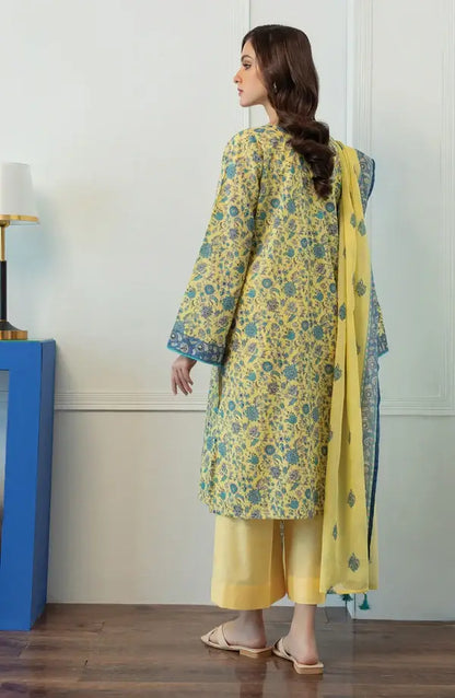 A woman wearing a yellow and teal floral printed traditional kurta set with matching pants and dupatta, shown from the back in an indoor setting.