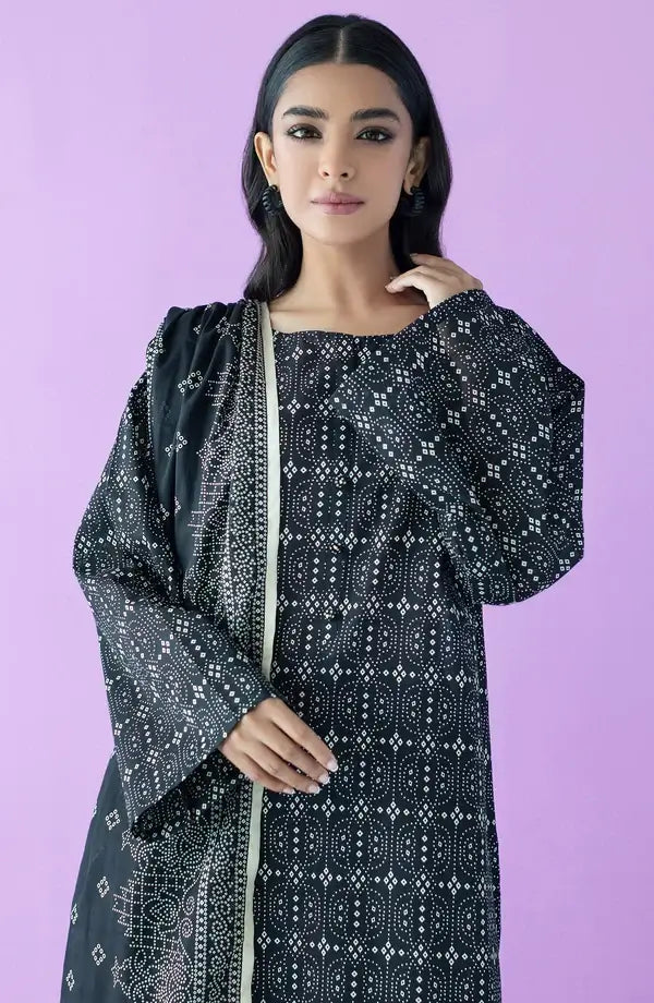 A woman modeling a black long kurta with white geometric bandhani-style prints and a matching black dupatta, set against a solid lavender-purple studio background.