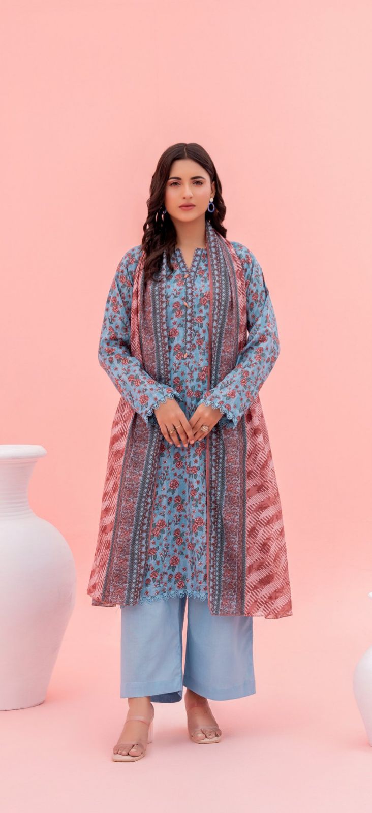 Woman wearing a floral kurta with a pink dupatta on a pink background