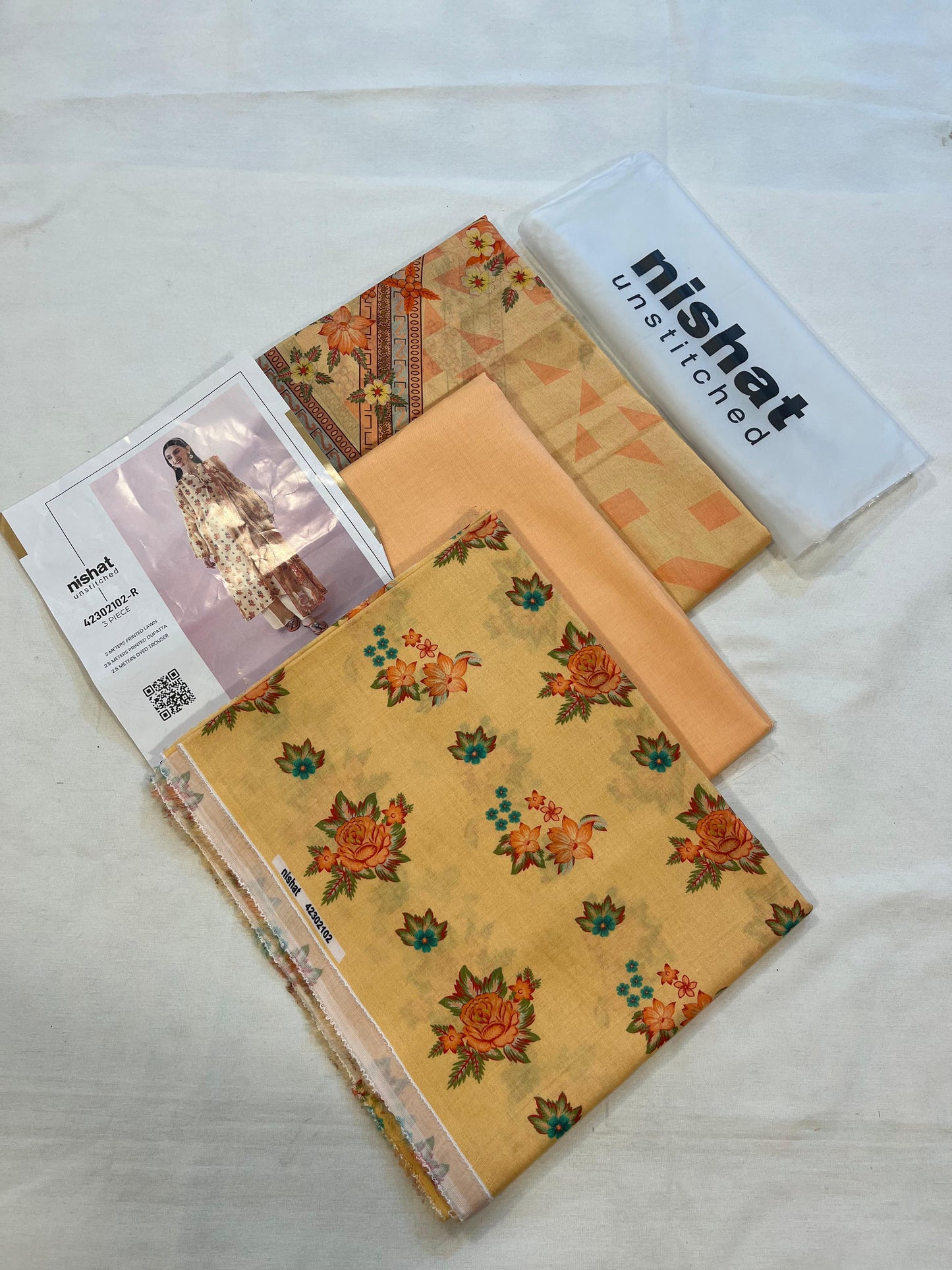 Nisha By Nishat 3pc Unstitched Lawn - Orange, includes fabric pieces and a printed shirt catalog.